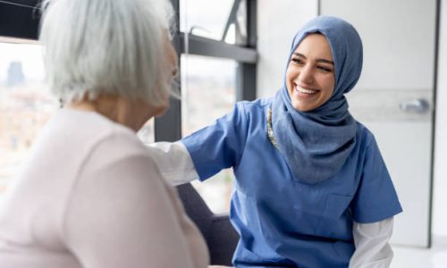 Muslim nurse talking to a senior patient at the hospital and smiling - healthcare and medicine concepts